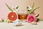 generate a modern product image displaying the following individual notes, with a pink/beige/taupe background: grapefruit, jasmine, rose, green stems, bourbon, musk, woods